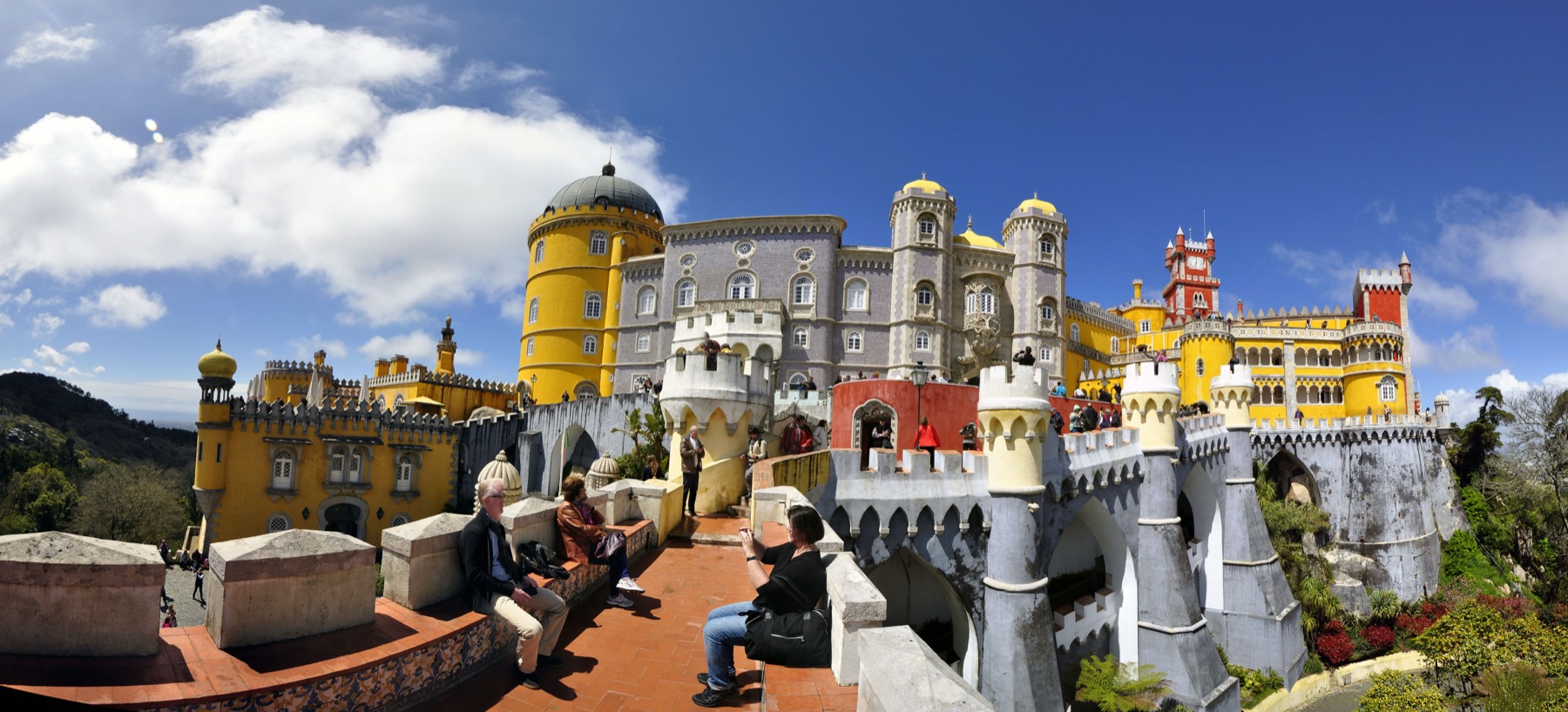 Les tours jaunes et rouges du palais de Pena à Sintra, sous un ciel bleu.